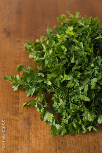 Bunch of fresh garden parsley stems with little imperfections on wooden background