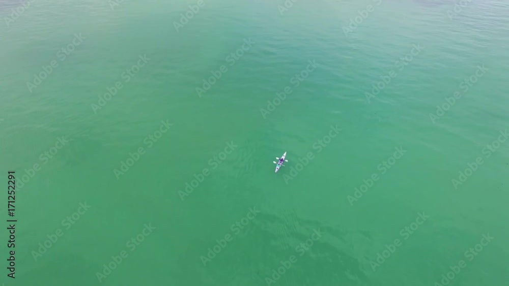 Forward flight over ocean water passing double kayak Forward flight over ocean water passing double kayak