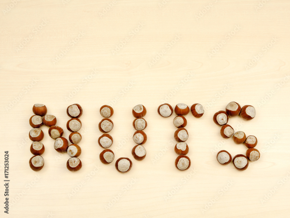Word NUTS spelled with various nuts on a wooden background. Word NUTS spelled with various nuts on a wooden background.