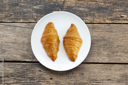 Croissant In white plate placed on a wooden table top view