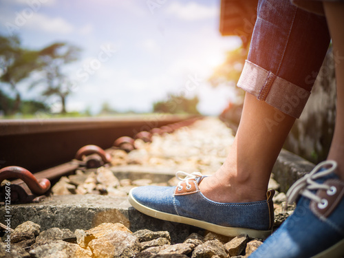 Closeup woman feet in blue sneakers sitting by the railway. Vacation and travel concept.