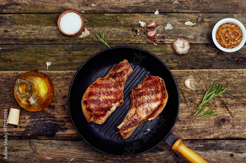 Grilled pork chops in a grill pan  on an old wooden table. Top view, flat lay.