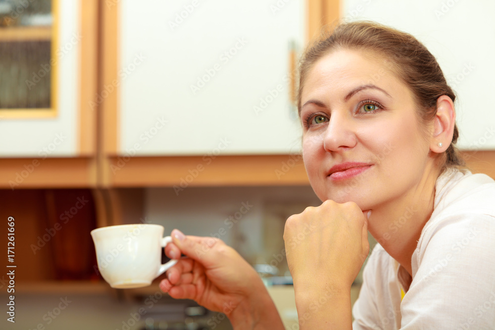 Mature woman holding cup of coffee in kitchen. Mature woman holding cup of coffee in kitchen.
