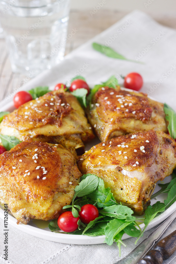 Baked chicken thighs with garnish of arugula and tomatoes. Rustic style, selective focus.