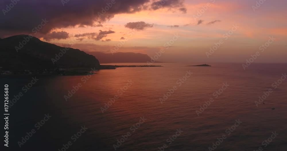 A pink sunset near the sea, the sun went beyond the horizon and illuminated the sky and mountains A pink sunset near the sea, the sun went beyond the horizon and illuminated the sky and mountains