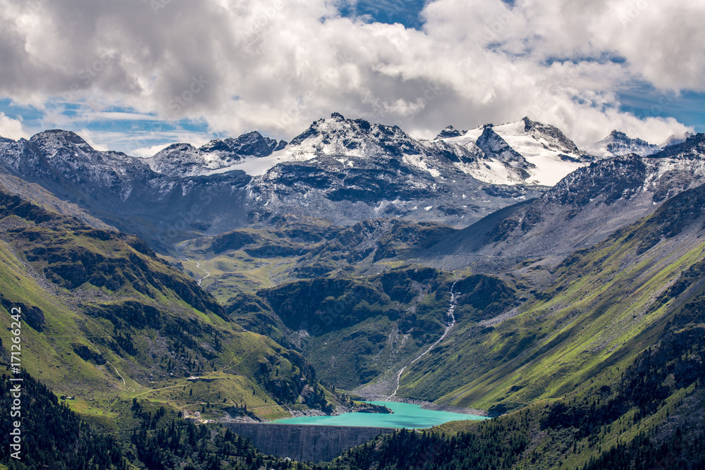 un lac bleu et un barrage au pied des montagnes enneigées suisses