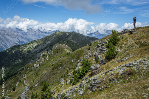 une jeune femme sur le haut d'une colline devant un paysage alpin