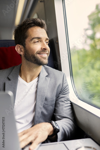 Handsome guy on train using laptop, smiling © sanneberg