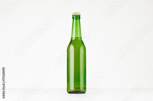 Green longneck beer bottle 500ml, mock up. Template for advertising, design, branding identity on white wood table.