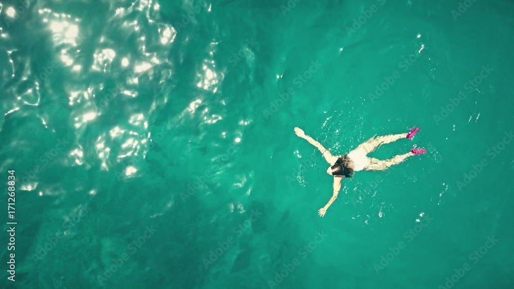 Obraz premium Aerial top down view of a beautiful young woman swimming in the sea
