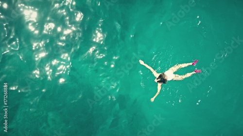 Aerial top down view of a beautiful young woman swimming in the sea