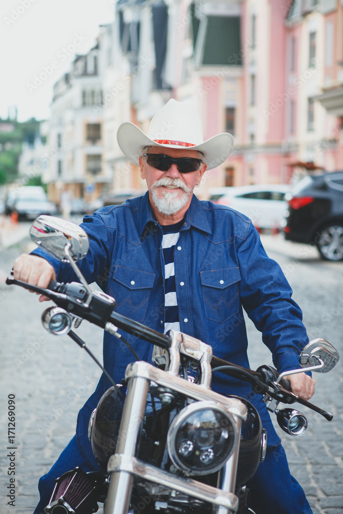A man on a motorcycle, wearing a cowboy hat.