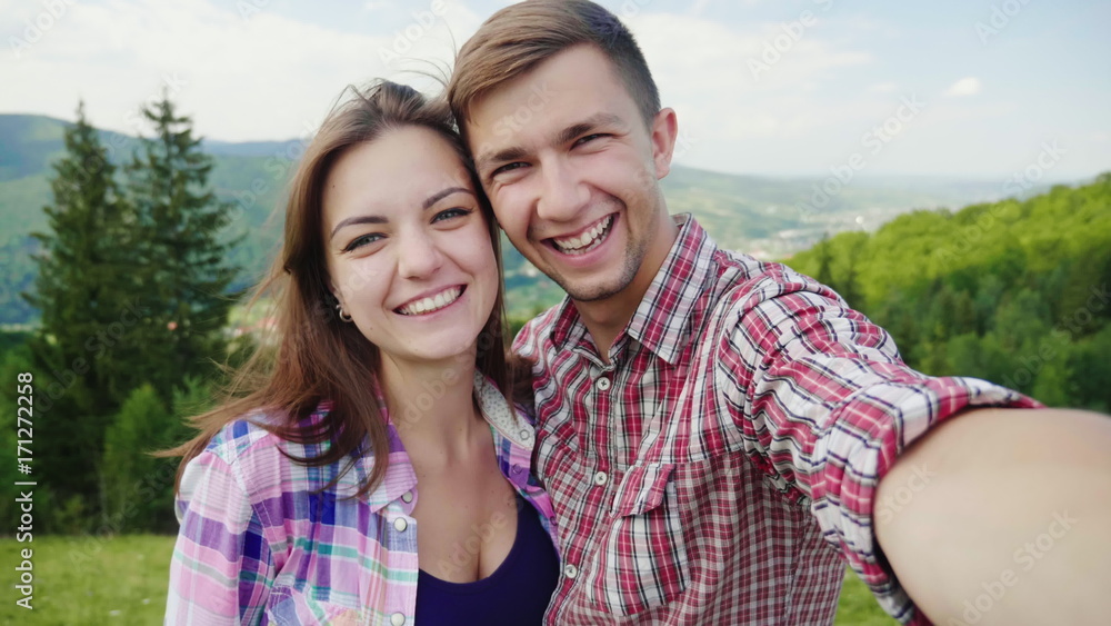 Happy couple doing selfie on a background of beautiful mountains. Magnificent vacation and vacation. 4K slow motion video Happy couple doing selfie on a background of beautiful mountains. Magnificent vacation and vacation. 4K slow motion video