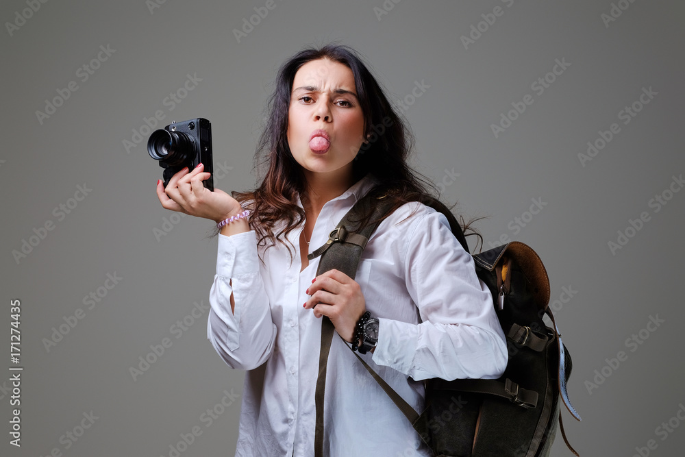 Female holds digital photo camera and a tripod.
