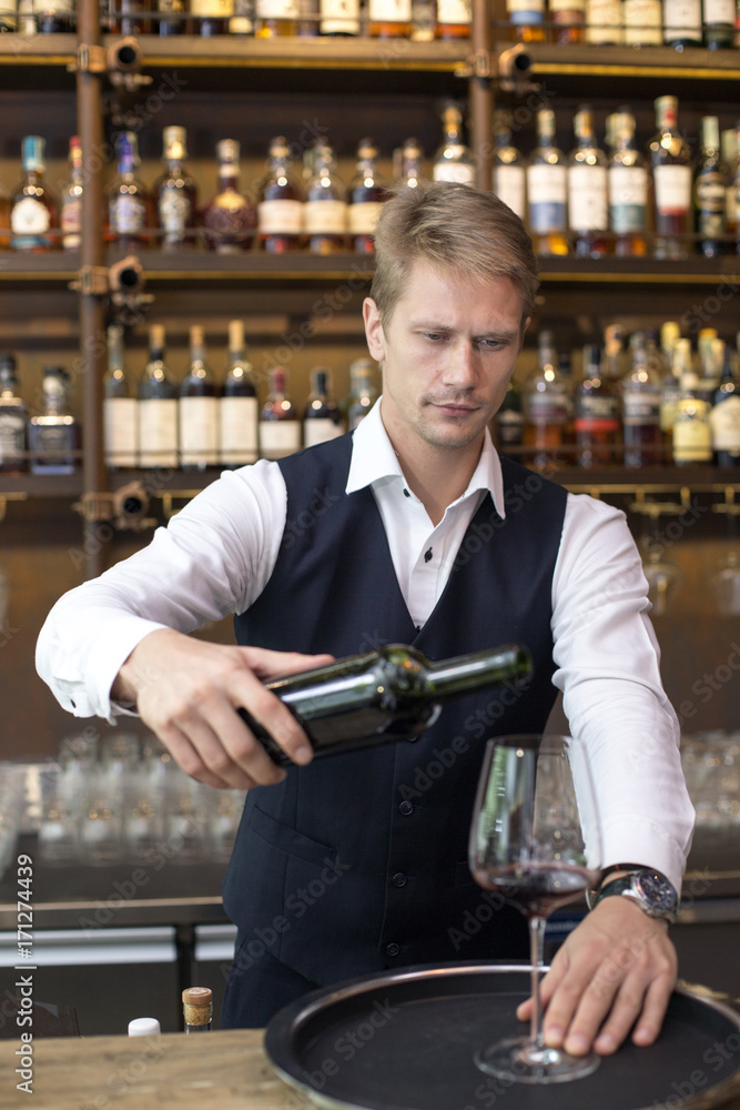 Handsome sommelier man Pour wine to the glass in restaurant, Man present Wine to Customer, Man with Sommelier Concept.