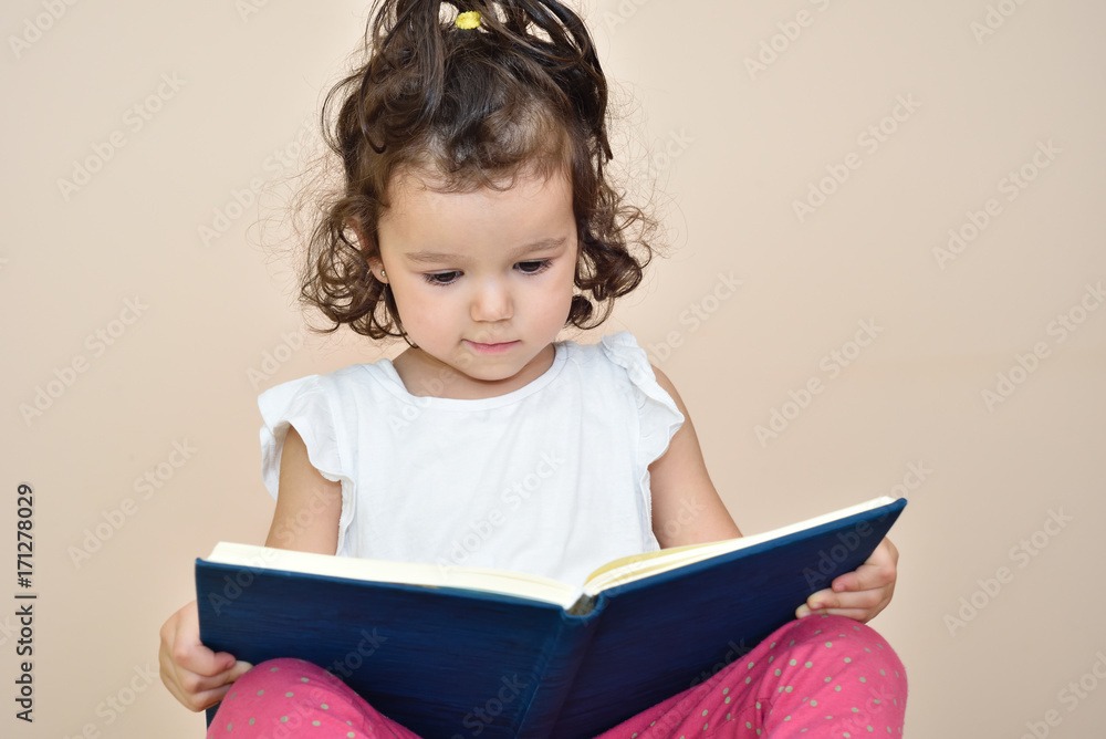 Talented cute three-year-old girl reading a book. Selective focus. Talented cute three-year-old girl reading a book. Selective focus.
