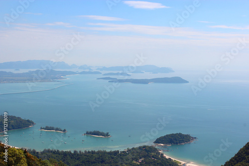 An observation deck on top of a mountain. View of the blue lagoon with yachts and boats, green hills and blue sky