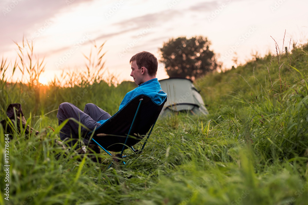 Young man sitting at campsite during sunset. Young man sitting at campsite during sunset.