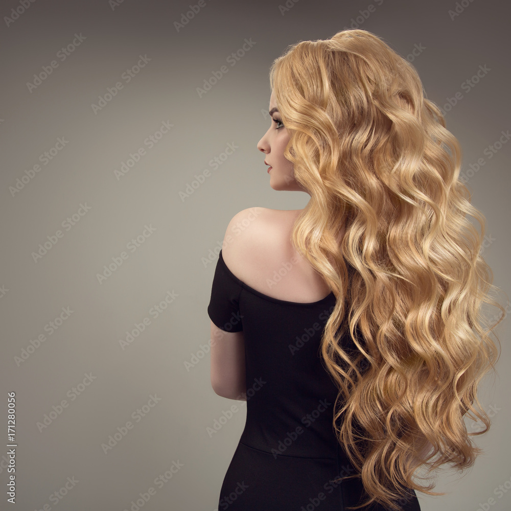 Fototapeta premium Blond woman with long curly beautiful hair. Back view.