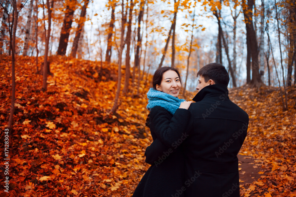 Young man and woman hugging in the Park, red leaves on trees, October