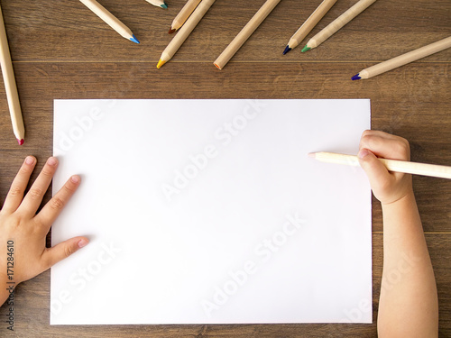 Kid holding a pencil over empty white sheet of paper