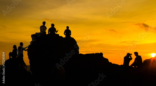 Asian tourists Waiting for sunset On a rock Golden sunlight on the sea and mountains,Nang Phaya Hill Scenic Point thailand