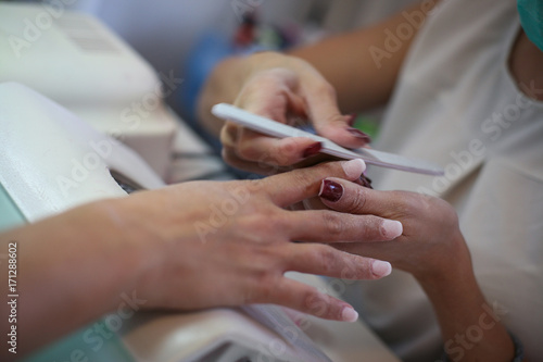Close-up of female hands being manicured in nail salon.