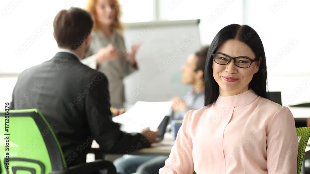 On front view brunette businesswoman smiling, showing ok with hand. Modern office, employees working on project. On front view brunette businesswoman smiling, showing ok with hand. Modern office, employees working on project.