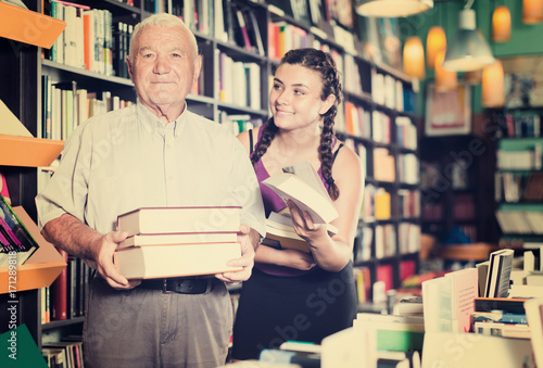 Old man with young woman are showing books