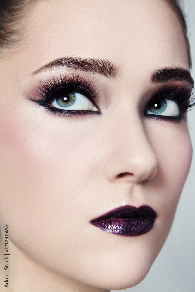 Close-up portrait of young beautiful woman with winged eye make-up make-up looking upwards Close-up portrait of young beautiful woman with winged eye make-up make-up looking upwards
