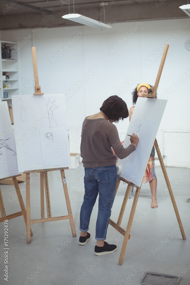 Female artist drawing a sketch of woman on canvas Female artist drawing a sketch of woman on canvas