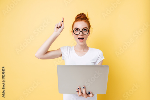 Happy ginger woman in eyeglasses holding laptop computer