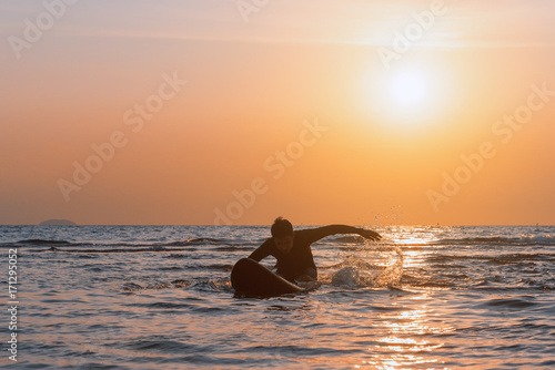 Man playing surfboard on the beach at sunset.