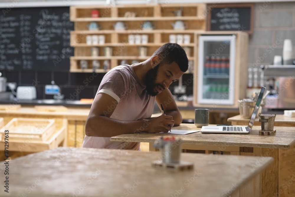 Young man writing while sitting in cafe Young man writing while sitting in cafe