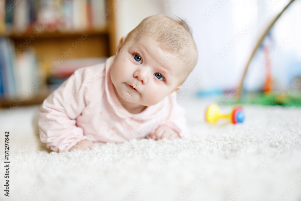 Adorable newborn baby girl lying on belly in white sunny bedroom or nursery Adorable newborn baby girl lying on belly in white sunny bedroom or nursery