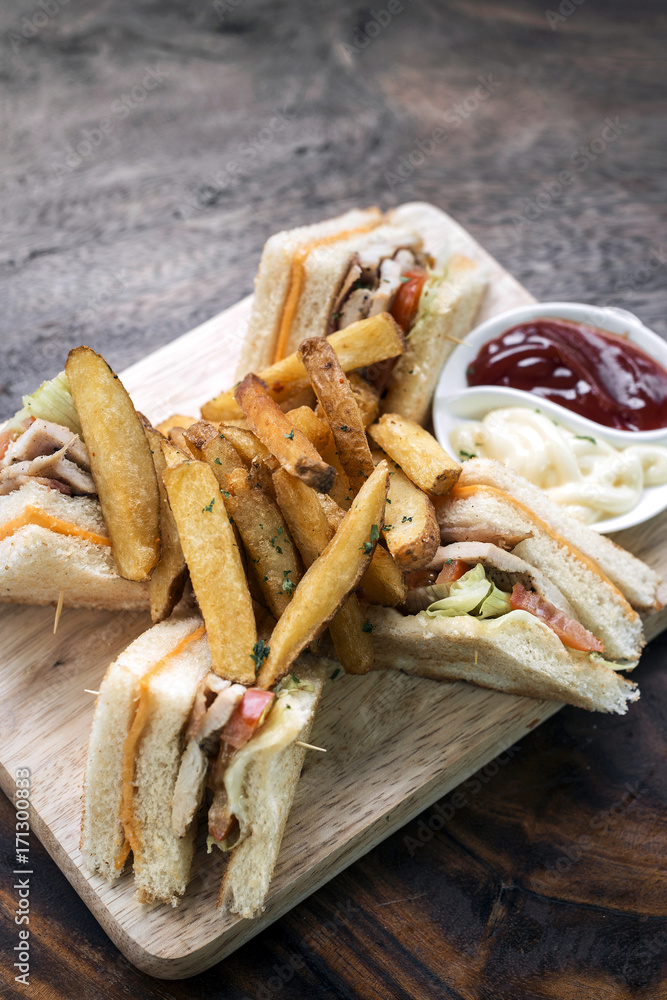 classic club sandwich with fries on wooden board classic club sandwich with fries on wooden board