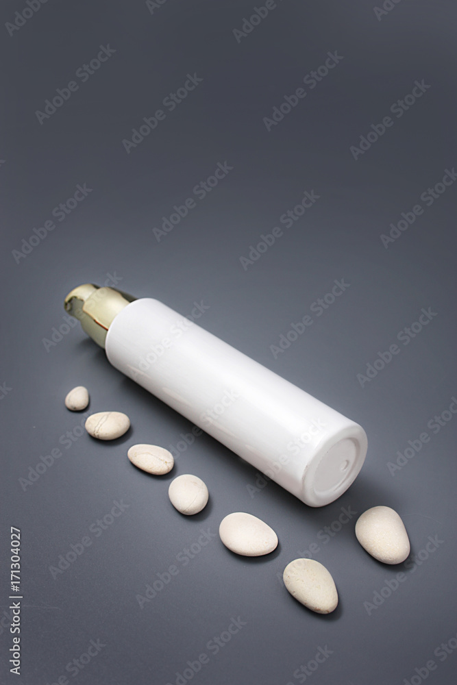 Cosmetics with a dispenser with stones on a gray background Cosmetics with a dispenser with stones on a gray background