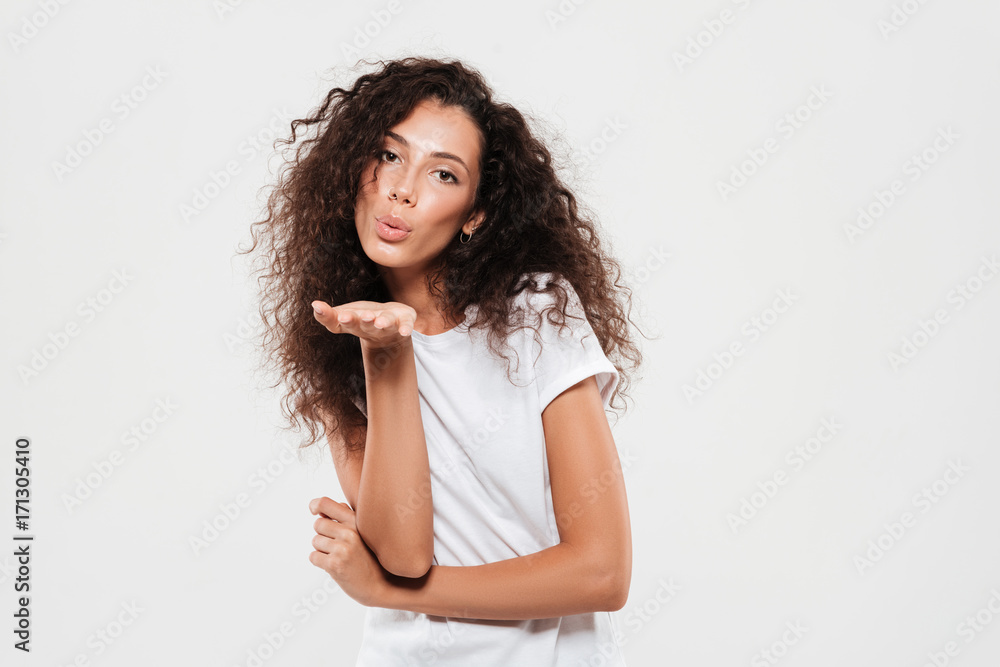 Pretty young woman with curly hair sending air kiss Pretty young woman with curly hair sending air kiss