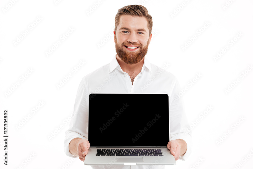 Bearded man standing over white wall showing display of laptop. Bearded man standing over white wall showing display of laptop.