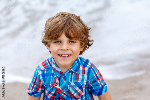 little kid boy running on the beach of ocean