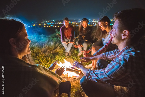 The five people warming hands near the bonfire. night time