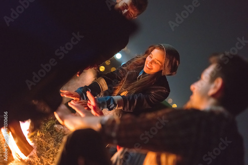The happy people warming hands near the bonfire. night time