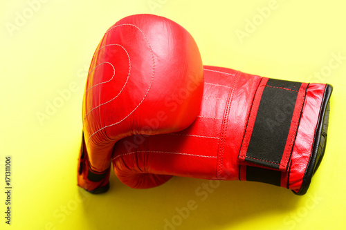 Two red boxing gloves made of leather on light yellow © be free