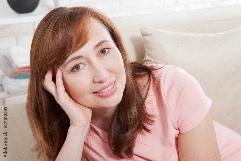 Macro portrait of smiling female face. Attractive and beautiful middle aged woman sitting on sofa and relaxing at home. Menopause Macro portrait of smiling female face. Attractive and beautiful middle aged woman sitting on sofa and relaxing at home. Menopause