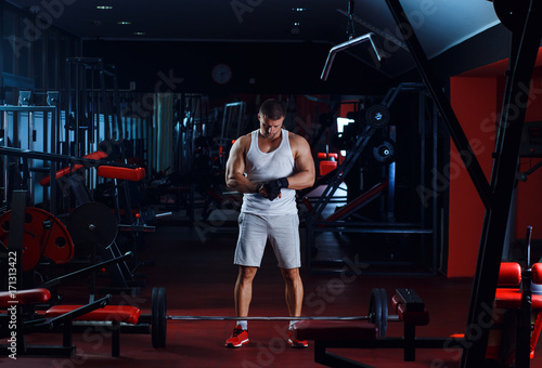 Young man exercising with weight in the gym.