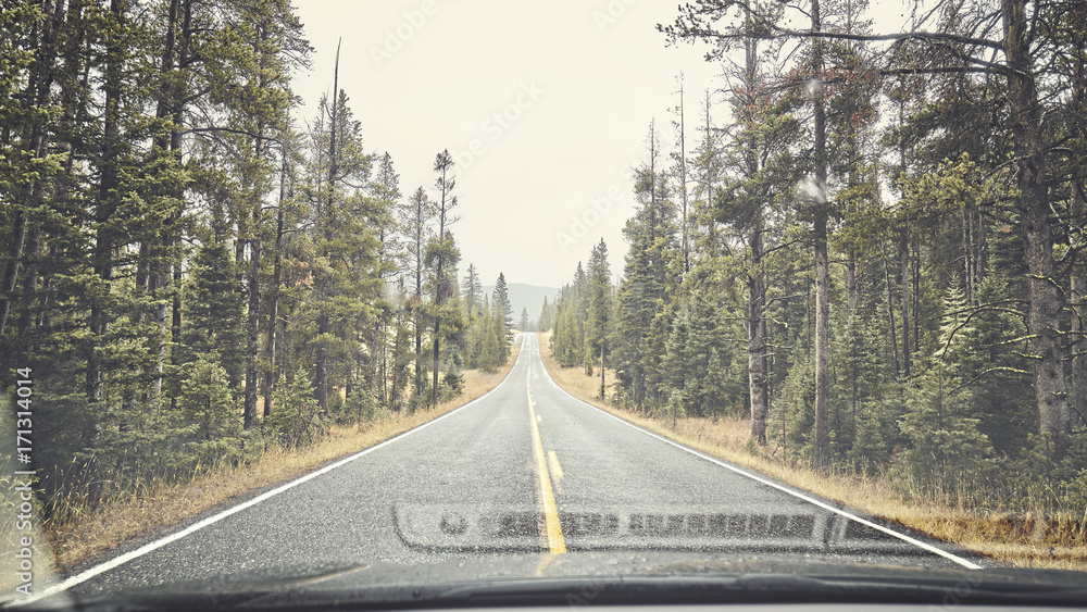 Fototapeta premium Mountain rainy road seen through the windshield, color toning applied, travel concept.