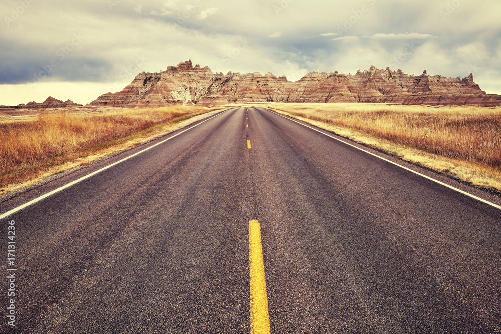 Fototapeta premium Vintage toned picturesque road in Badlands National Park, travel concept background, South Dakota, USA. 