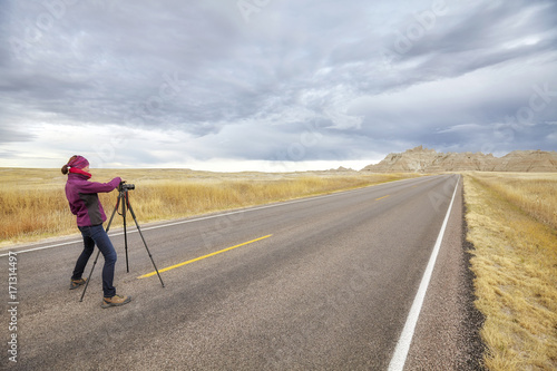 Landscape photographer takes pictures on an empty road with stormy sky  travel or work concept   Badlands National Park  South Dakota  USA.