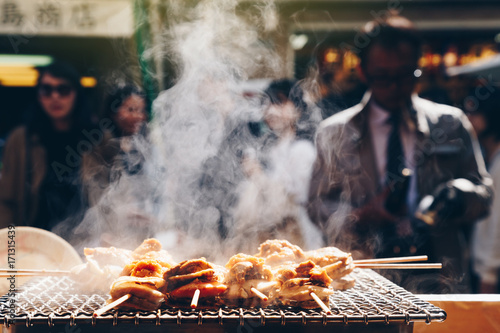 grilled seafood scallop and sea ​​urchin eggs skewer with smoke, japanese street food at Tsukiji Fish Market, Japan. selective focus and film style.