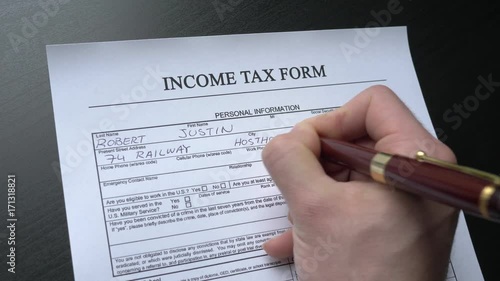 Filing an income tax form by hand at a desk. This form is randomly filled with no real names or numbers.